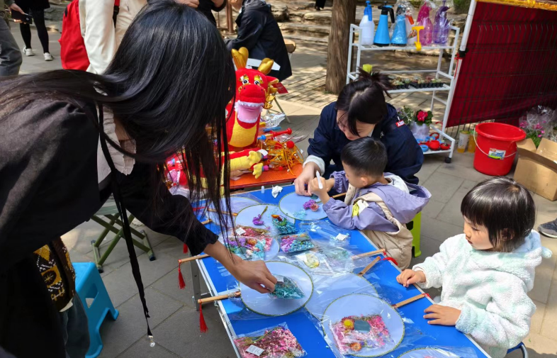 北京陶然亭公园开设的陶然市集上,小游客们正在体验画扇面。记者 乔业琼摄
